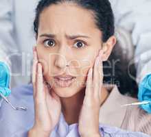 Trips to the dentists can be a nightmare. Shot of a young woman looking afraid at her dentists office.