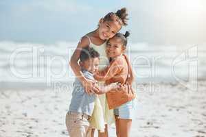 Adorable little girl hugging and embracing her two younger siblings at the beach. Big sister showing her little brother and sister love and affection