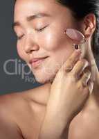 I noticed my skin had a tighter look and looked even younger. Studio shot of a beautiful young woman using a face roller on her skin.