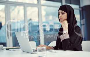 Shes determined to achieve her goals. an attractive young arabic businesswoman working on her laptop in the office.