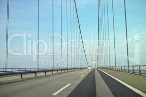 Storebaelt suspension bridge in Denmark against blue sky background. Overpass road crossing for transport to link travel destination routes. Infrastructure and architecture design of famous landmark
