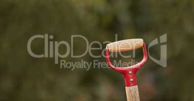 Closeup of a shovel handle in a garden outside against a blur background. Red gardening tool or equipment ready to be used in a backyard for shoveling, planting and basic outdoor maintenance