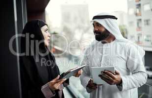 Together they can do twice the work. two young businesspeople dressed in Islamic traditional clothing using their tablets on the office balcony.