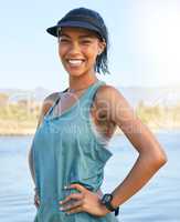 Fit young woman enjoying her time off on a holiday, vacation or weekend getaway outside on a lake or river. Athletic smiling female standing outdoors with her hands on her hips on a sunny day