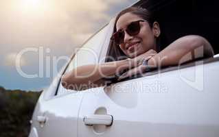 The road is where my heart is. Shot of a beautiful young woman enjoying an adventurous ride in a car.