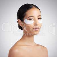 Studio Portrait of a beautiful mixed race woman wearing under eye patches. Hispanic model with glowing skin using hydrating treatment against a grey copyspace background