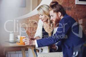 Young mixed race diverse colleagues meeting in a cafe while working on as a team on a project. Multiracial workers using a laptop to brainstorm while enjoying coffee and planning a new business idea