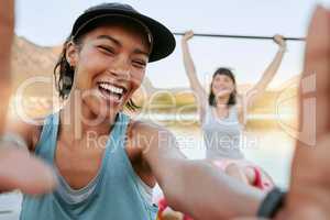 Two smiling friends taking selfies and kayaking together on a lake in summer break. Smiling happy playful women bonding outside in nature with water activity.