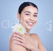 Studio portrait of a beautiful mixed race woman posing with a flower. Young hispanic using an organic skincare treatment against a blue copyspace background