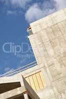 Exterior of a concrete building against a cloudy blue sky. Detail view of a tall residential or office building made of exposed concrete slabs. Construction phase of home remodel and addition