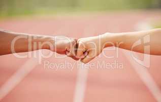 Youve got this. two unrecognizable athletes fist bumping while standing out on track.