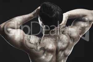 Strong body, strong mind. Monochrome shot of a muscular young man posing nude in studio against a dark background.