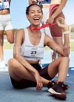 Portrait of a cheerful athletic woman showing gold medal from competing in sports event. Smiling fit active latino athlete feeling proud after winning running race. Track runner achieving goal