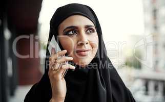 Thinking about what shes hearing. an attractive young businesswoman dressed in Islamic traditional clothing making a phonecall while standing on her office balcony.