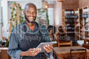 Young african american businessman working in a retail store using a digital tablet device. Portrait of a smiling small business owner, entrepreneur buying stock online using wireless technology