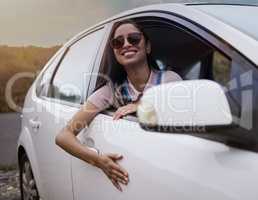 Sure is better than walking. Shot of a beautiful young woman enjoying an adventurous ride in a car.