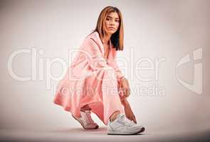 Portrait of a young mixed race female posing in trendy fashionable clothing while chilling on a floor of a studio. Hispanic woman showing the latest fashion collection with a cool style and sneakers