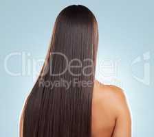 Rear view of a brunette woman with long lush beautiful hair posing against a grey studio background. Mixed race female standing showing her beautiful healthy hair