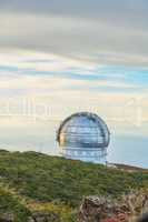 Scenic view of an astronomy observatory dome in Roque de los Muchachos, La Palma, Spain. Landscape of science infrastructure or building against blue sky with clouds and copyspace abroad or overseas