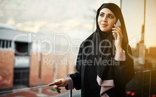 Success is about communication. an attractive young businesswoman dressed in Islamic traditional clothing making a phonecall while standing on her office balcony.