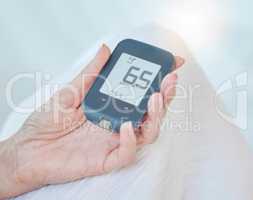 Closeup of a senior diabetic woman checking her blood sugar glucose levels with a diabetes reading strips machine. One unknown elderly woman doing a blood sugar reading at home