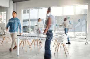 Group of diverse businesspeople walking around in a busy office at work. Business professionals rushing while working together in an office. Four colleagues getting work done in an office