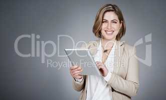 It benefits my personal and professional life. Studio portrait of a young businesswoman using a digital tablet against a gray background.