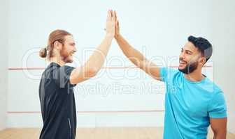 Two athletic squash players giving high five before game on court. Team of fit active caucasian and mixed race male athletes using hand gesture before competing and training together in sports centre