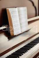 Closeup of a vintage piano and keyboard with a sheet music book. An empty antique or wooden musical instrument for playing classical jazz or used for old traditional songwriting and rehearsals