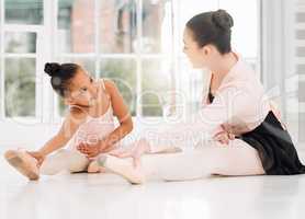 A good stretch to start todays lesson. a ballet teacher and student taking a break and talking on the floor of a dance studio.