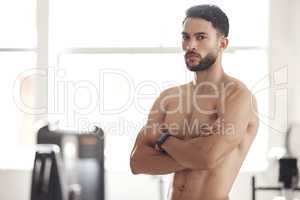 Portrait of one fit young topless hispanic man with big strong muscles from regular exercise standing with arms crossed in a gym. Serious bodybuilder with toned and sexy physique. Brawny athlete proud of physical progress and powerful form