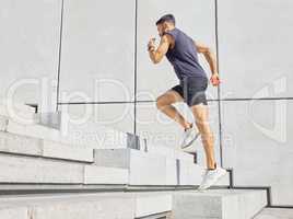 Head up and aim high. Low angle shot of a sporty young man running up a staircase while exercising outdoors.