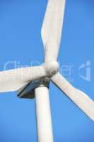 Renewable and sustainable energy generated by a modern wind turbine against a blue sky background outside. Wind energy or power generating clean electricity or mechanical power using rotating blades