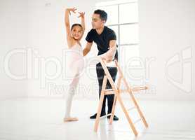 She always looks forward to her weekly ballet lessons. a ballet teacher assisting a student with her position in a dance studio.