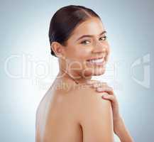 Portrait of beautiful woman with smooth glowing skin and copyspace posing topless and touching shoulder. Smiling caucasian model isolated against a grey studio background with healthy skincare routine
