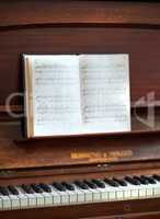 Closeup of a vintage piano and keyboard with a sheet music book. An empty antique or wooden musical instrument for playing classical jazz or used for old traditional songwriting and rehearsals