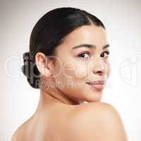 Face of a young beautiful mixed race woman smiling and posing against a grey studio background. Confident hispanic female posing against a background