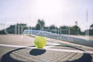 Below shot of a tennis racquet and tennis ball on a sports court. The only tools a professional tennis player needs to participate in their chosen sport. Six games per set to see who wins the match