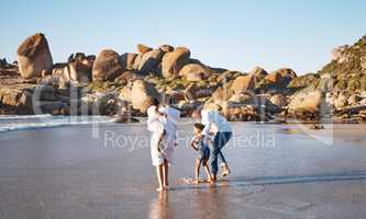 Happy young african american family with two children spending time together and having fun at the beach getting their feet wet. Loving parents enjoying family vacation with little daughter and son