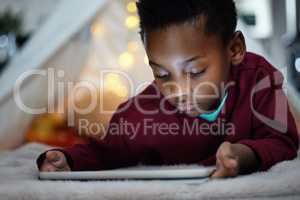 How late is too late. an adorable little boy using a digital tablet during bedtime at home.