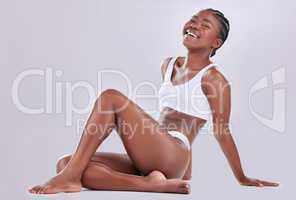 Acceptance is the key to inner peace. Shot of a happy young woman sitting on the floor against a studio background.