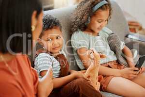 Closeup of a mixed race single parent teaching her son a lesson about sharing while his sister is using a cellphone and headphones. A single parent putting her son in timeout for his bad behaviour
