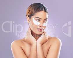 Just have to wait it out. Shot of a young woman using eye masks against a pink background.