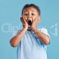 Adorable little hispanic boy with hands on face and mouth open looking terrified and shocked showing true astonished reaction against a blue studio background