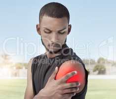 Closeup of an athlete with shoulder pain after a workout. Side profile of a young sportsman standing on a field holding his stiff and inflamed joint. Muscle strain highlighted in red due to injury