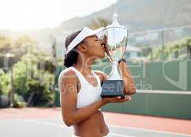 Youre coming home with me. a sporty young woman kissing a trophy that she won in a tennis match.