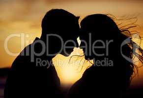 Silhouette couple enjoying romantic moment with their foreheads touching against sunset background. Unknown boyfriend and girlfriend feeling in love while bonding outside. Man and woman gently hugging