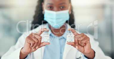 Medical doctor holding bottles of the covid cure. Ready to save the world from covid. African American doctor holding vials of the corona virus antidote.Healthcare professional wearing a mask