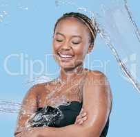 Sustenance is found in the water. Studio shot of an attractive young woman being splashed with water against a blue background.