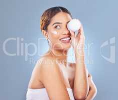 Getting all the moisture. Shot of a young woman applying lotion to her face against a grey background.